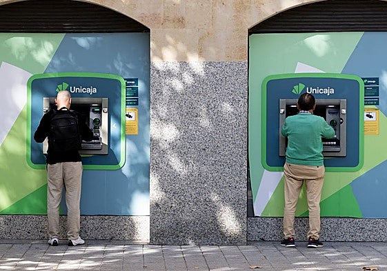 Dos ciudadanos, uno joven y otro de mediana edad, sacan dinero en sendos cajeros de la plaza de San Miguel el pasado miércoles.