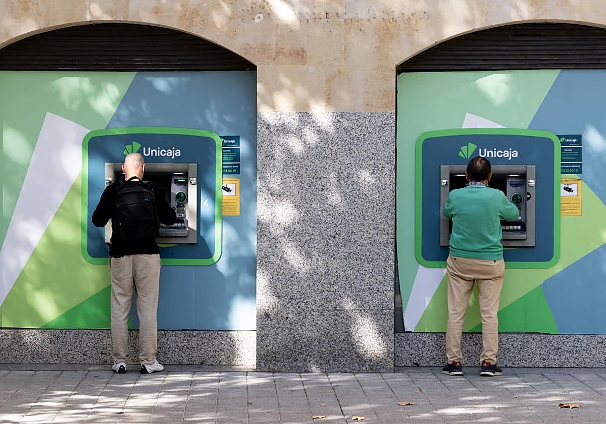 Dos ciudadanos, uno joven y otro de mediana edad, sacan dinero en sendos cajeros de la plaza de San Miguel el pasado miércoles.