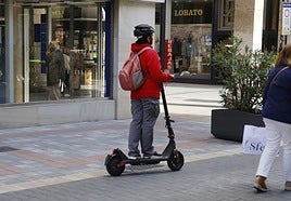 Una mujer con un patinete, en la calle La Cestilla.