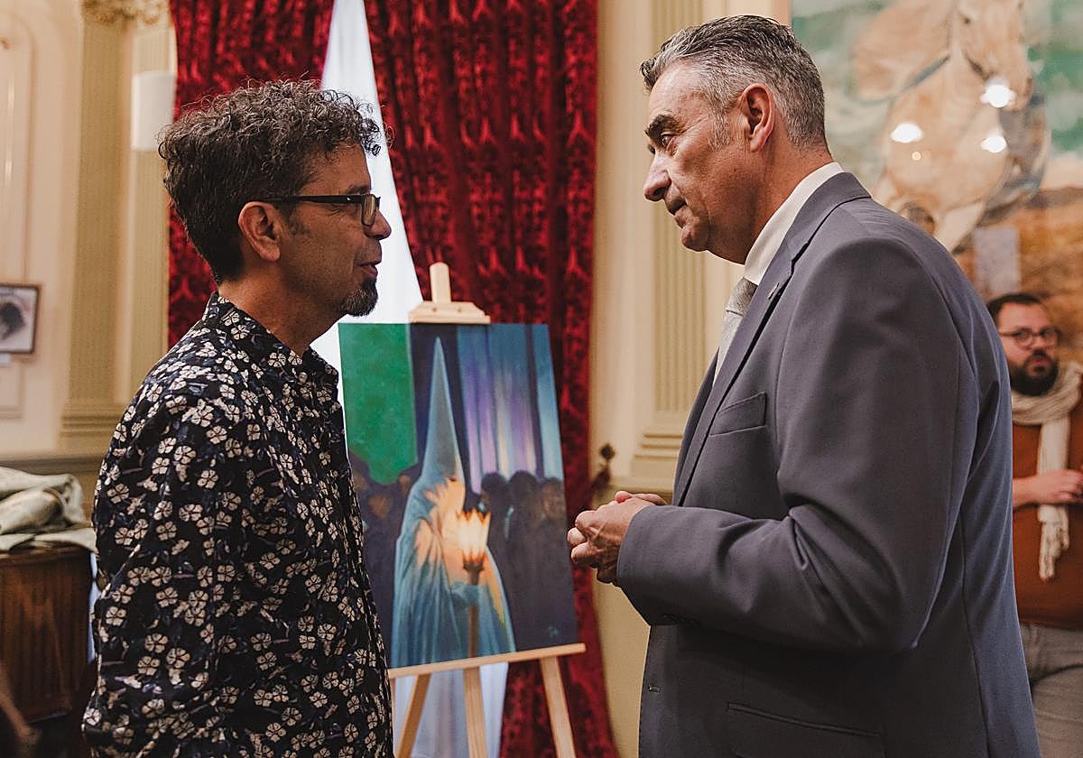 El pintor Santiago Lorenzo conversa con el presidente de los cofrades, Ricardo Fernández, ante el cuadro anunciador de la Semana Santa.