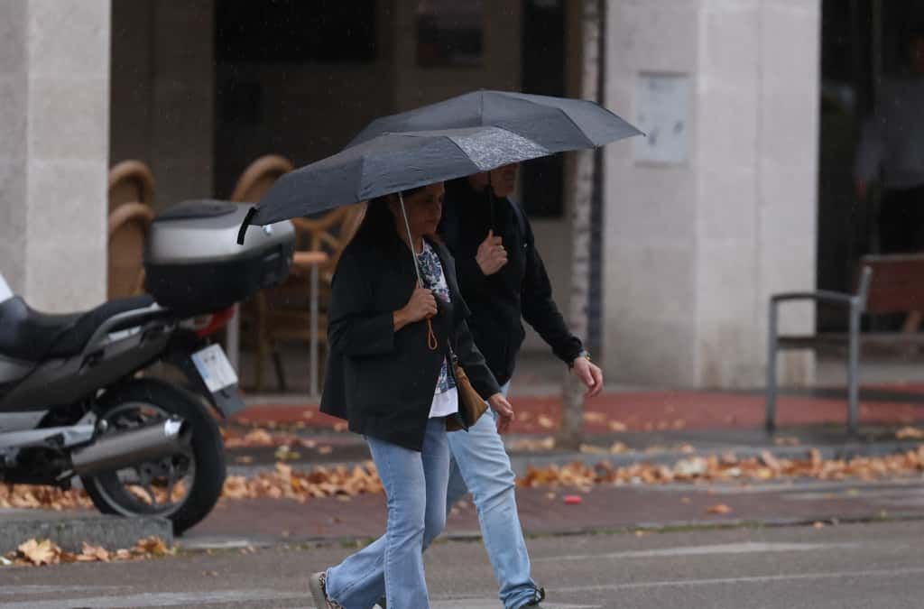 Dos personas caminan bajo sus paraguas cuando empiezan a caer las primeras gotas.