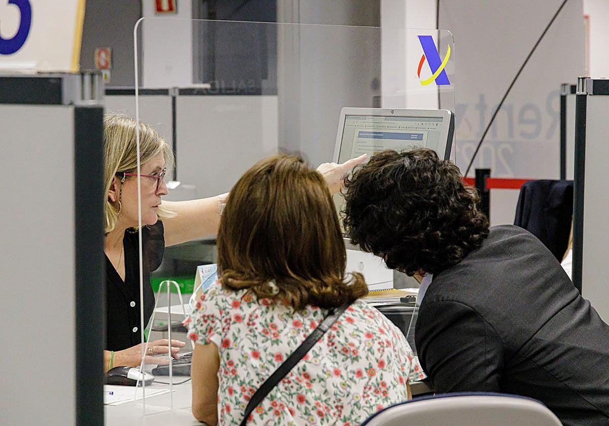 Dos contribuyentes ante una ventanilla de la Agencia Tributaria.