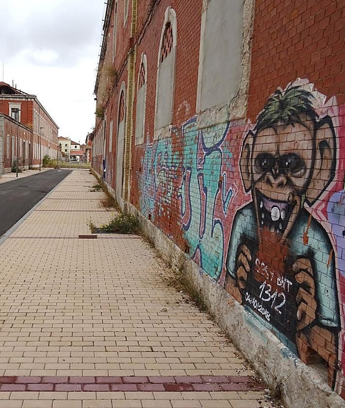 Imagen secundaria 2 - Arriba, dos jóvenes pasean por una de las nuevas calles del interior del Conde Ansúrez, en la que se han colado los primeros coches. Debajo, a la izquierda, la futura plaza de la Dignidad Humana. A la derecha, un viejo grafiti en una de sus calles.