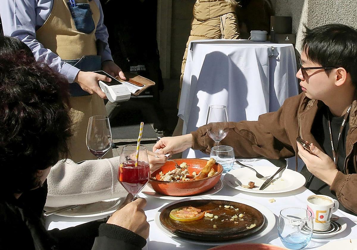 Un turista paga con tarjeta un almuerzo en un restaurante de la capital segoviana.