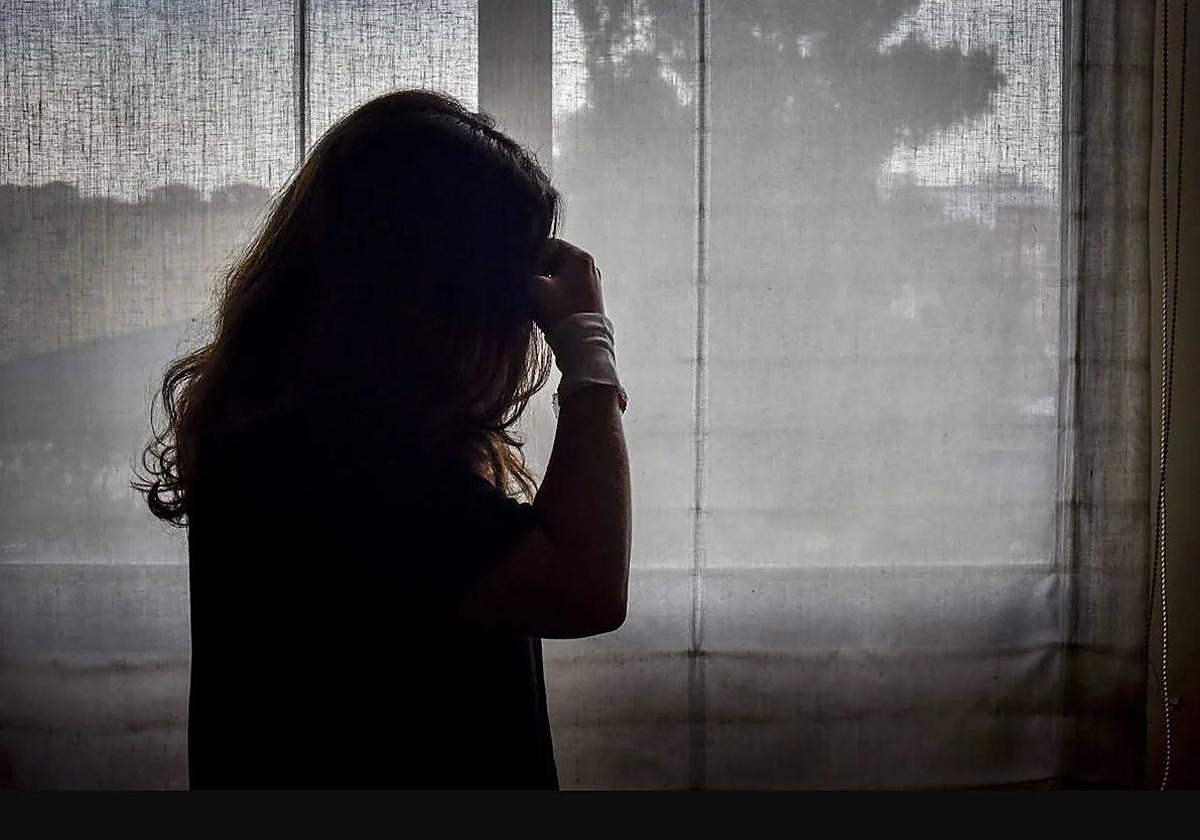 Imagen a contraluz de una mujer con la muñeca vendada por un intento de suicidio.