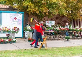 Un hombre lleva útiles de limpieza, a la entrada al cementerio, donde están instalados los puestos de venta de flores.