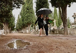 Dos mujeres llevan flores a una tumba del cementerio de El Carmen.