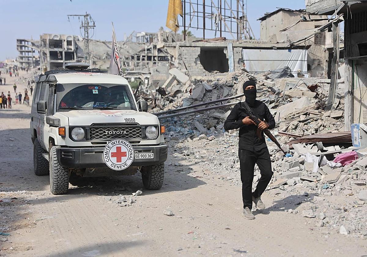 Un militante de Hamás junto a un vehículo de la Cruz Roja buscan cadáveres en Gaza.