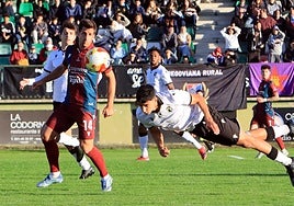Un jugador del Burgos Promesas intenta despejar un balón ante la mirada de Fer Llorente.