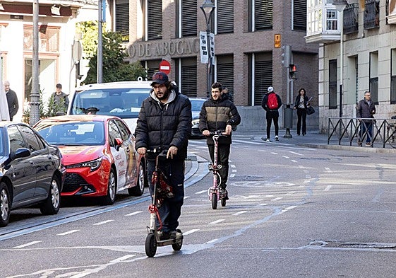 Dos usuarios de patinete eléctrico circulan por la calle Angustias.