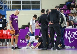 Dos chicos de la cantera se afanan para secar la zona más encharcada por las goteras del pabellón Pisuerga.