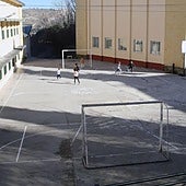 Escolares juegan en un patio del colegio la Aneja con varios desperfectos en el firme.