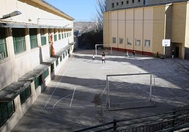 Escolares juegan en un patio del colegio la Aneja con varios desperfectos en el firme.