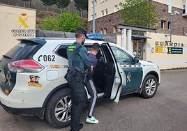 Un guardia civil introduce en el vehículo patrulla a uno de los detenidos.