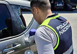 Un agente busca huellas en el turismo desvalijado.