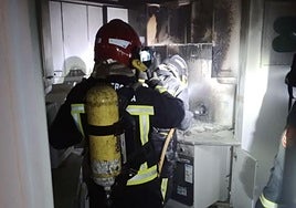Los bomberos extinguen el incendio en el interior de la vivienda.