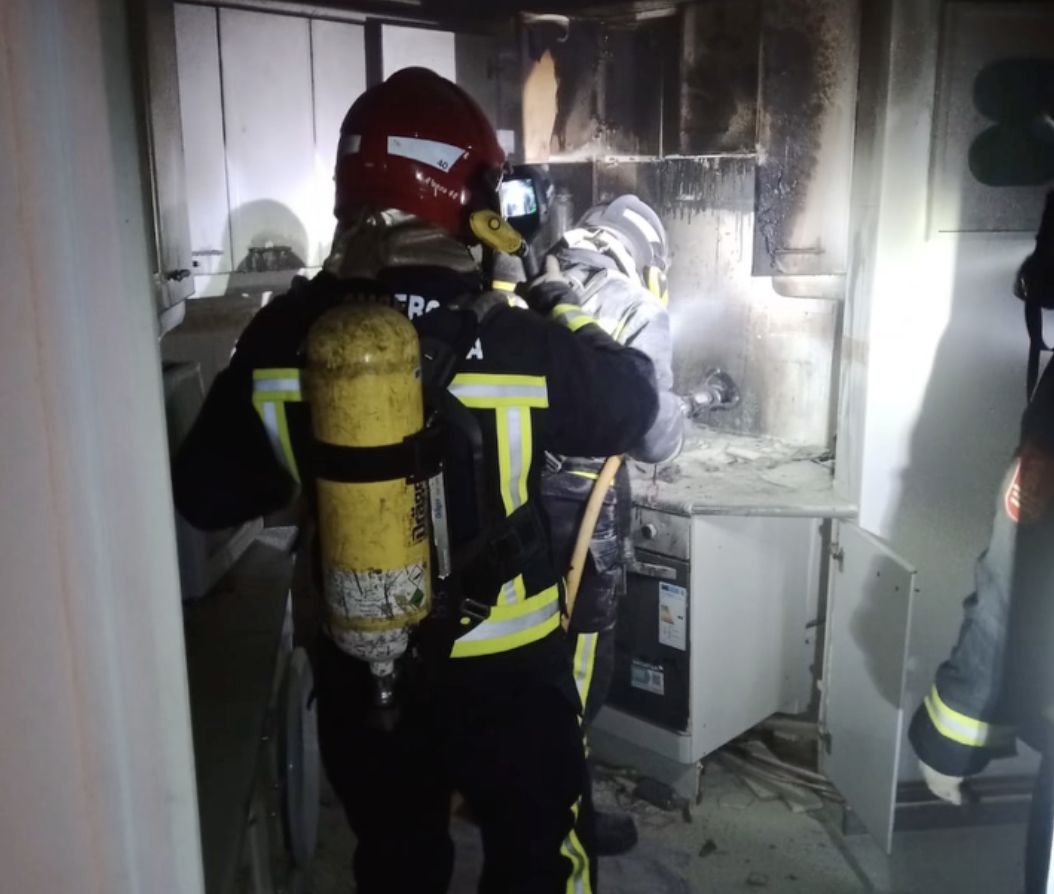Los bomberos extinguen el incendio en el interior de la vivienda.