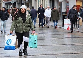 Viandantes por la Calle Mayor con bolsas de distinstos comercios.