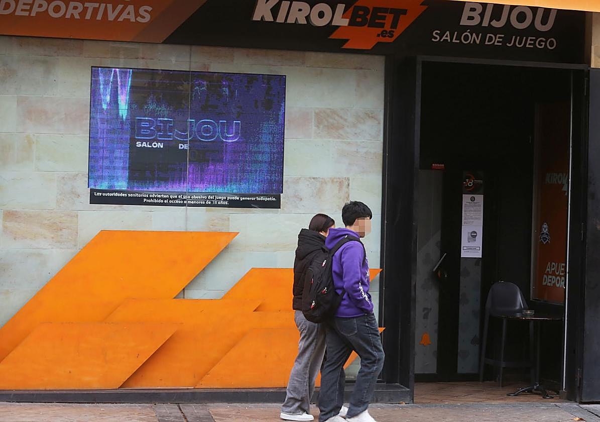 Dos personas caminan junto al acceso a un salón de juego.
