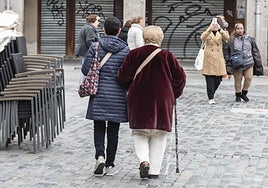 Una mujer acompaña a una anciana con bastón por la Plaza Mayor de Segovia.