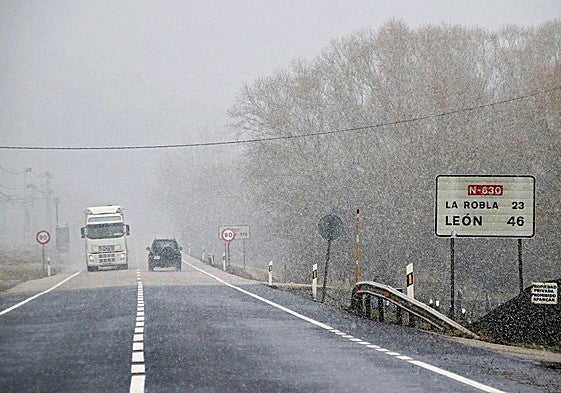 Varios vehículos circulan por una carretera nevada de León.