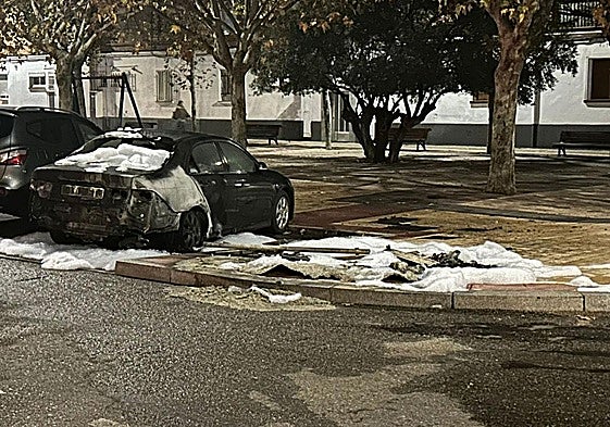 Coche dañado por el incendio con los restos de espuma tras la intervención de los bomberos en Amor de Dios.