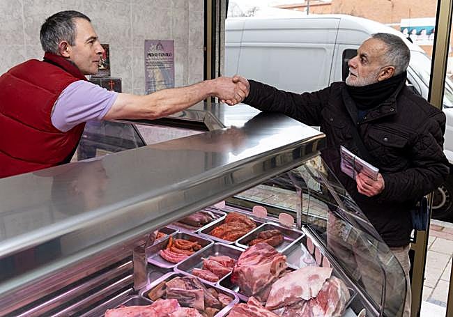El carnicero se despide de un cliente que entró a desearle lo mejor.
