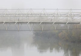 La pasarela del Museo de la Ciencia sobre el Pisuerga cubierto por la niebla en la mañana del lunes.