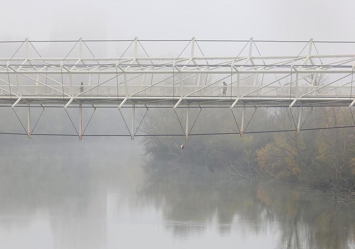 La pasarela del Museo de la Ciencia sobre el Pisuerga cubierto por la niebla en la mañana del lunes.