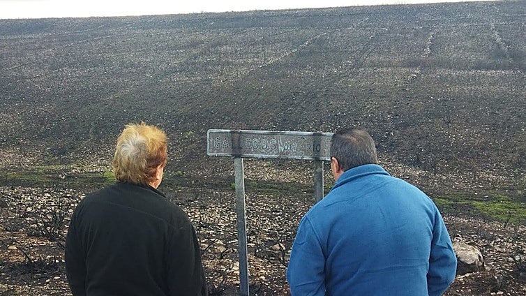 El alcalde (izqda) y un vecino de Puercas divisan el cartel quemado de Gallegos del Río.