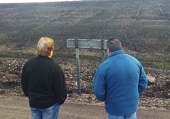 El alcalde (izqda) y un vecino de Puercas divisan el cartel quemado de Gallegos del Río.