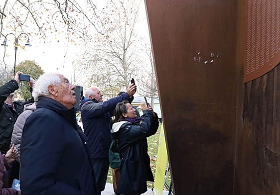 Varias personas fotografían la placa con los nombres de los represaliados franquistas.