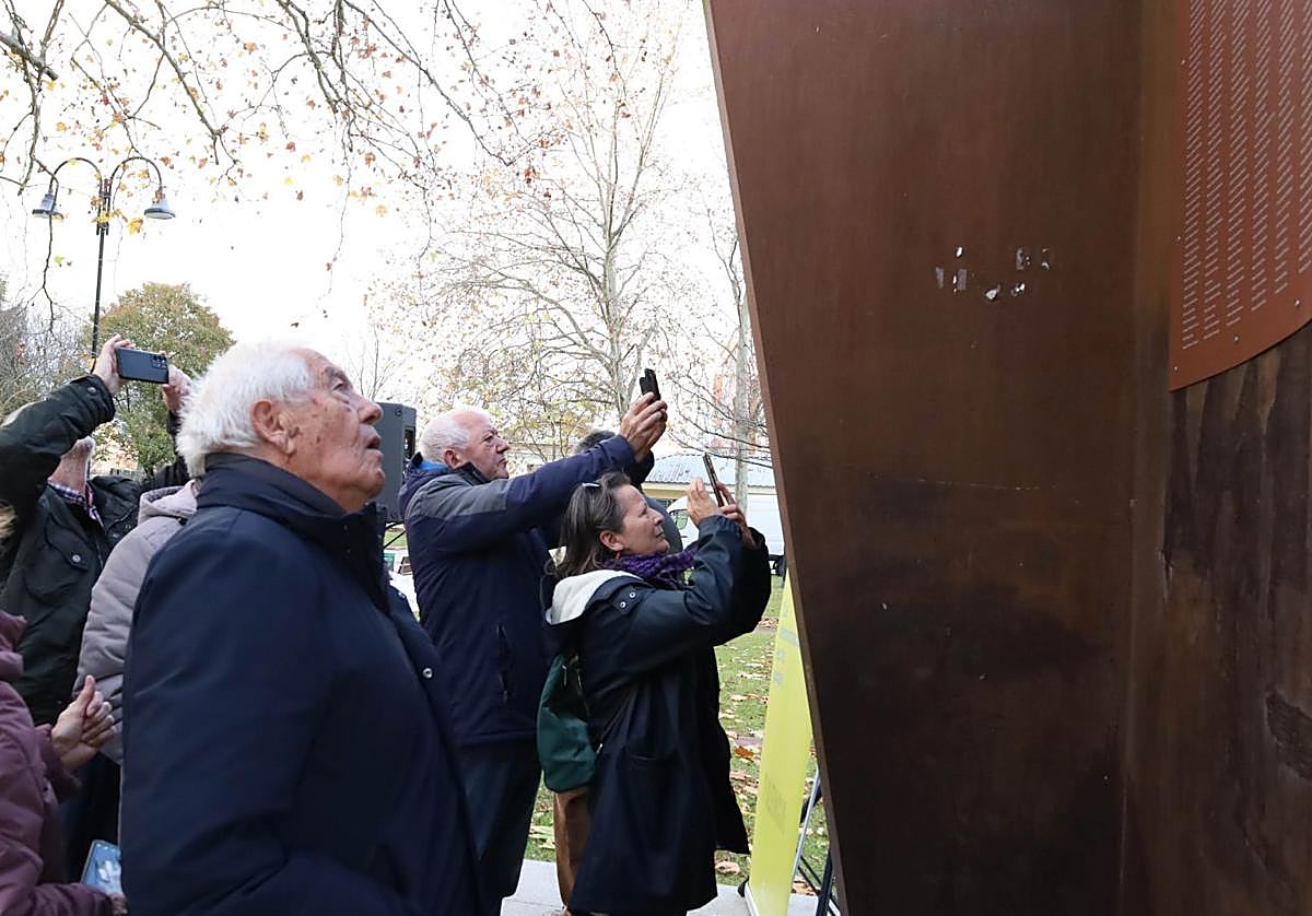 Varias personas fotografían la placa con los nombres de los represaliados franquistas.