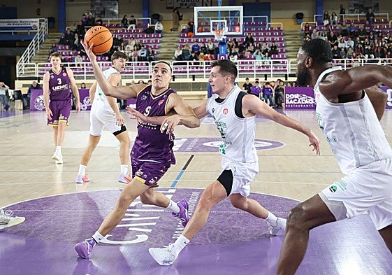 Pau Isern aleja el balón de su par en su entrada a canasta.
