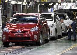 Un trabajador revisa varios Toyota Prius en una planta de Japón. / Afp