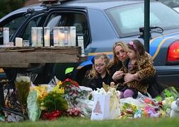 Una madre y sus dos hijas depositan flores en memoria de las víctimas. / Afp