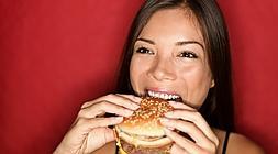 Mujer devorando una hamburguesa. / Archivo