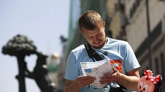 Un turista consulta un mapa en la Puerta del Sol. 