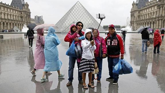 Una familia se hace un  frente al Louvre. 