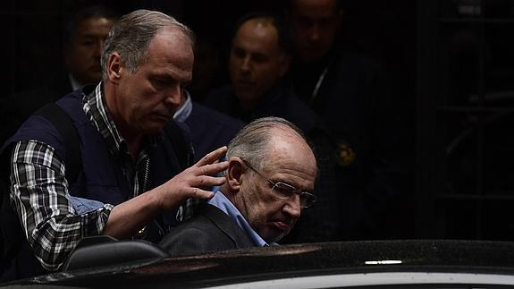 Un agente ayuda a Rodrigo Rato a entrar en el vehículo policial.