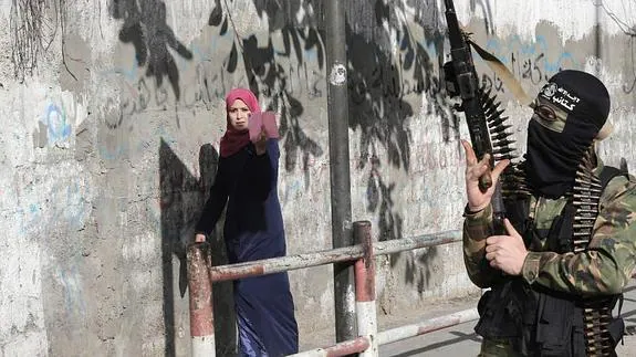 Una mujer fotografiando a un soldado palestino. 