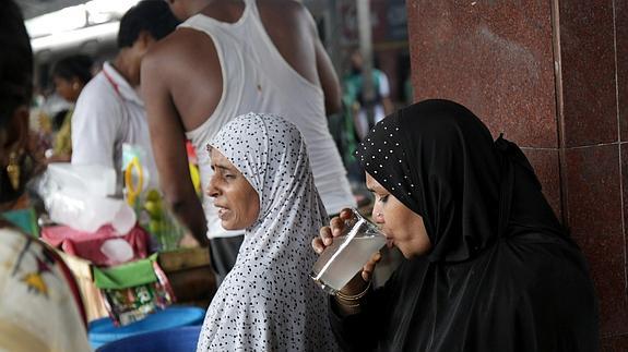 Una mujer bebe un vaso de agua en Calcuta. 