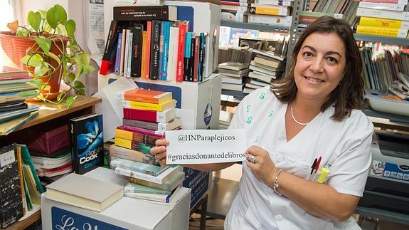 La bibliotecaria del Hospital de Parapléjicos de Toledo posa junto a los libros donados.