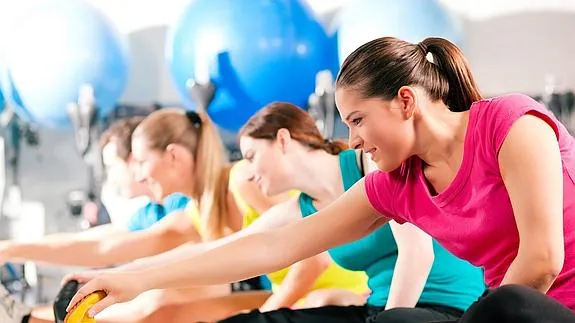 Mujeres haciendo ejercicios de estiramiento en un gimnasio. 