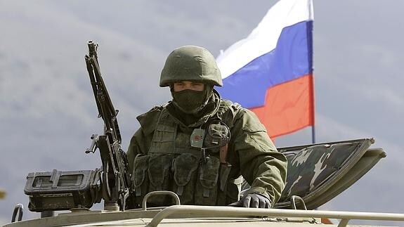 Un soldado en un tanque con una bandera rusa al fondo. 