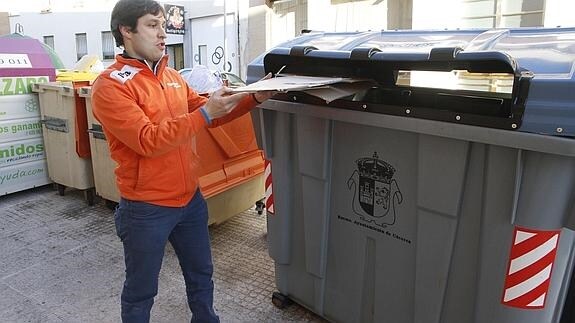 Un joven deposita papel en un contenedor.