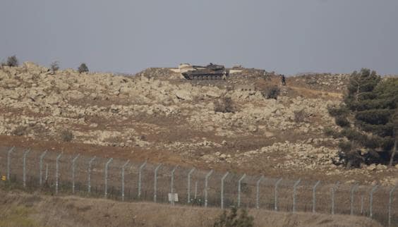 Rebeldes sirios junto a un tanque en la valla fronteriza próxima a la ciudad de Jubata, en Siria.