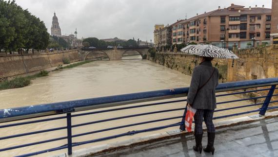 Una mujer observa la crecida del río Segura. 