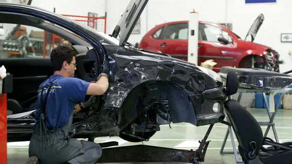 Un trabajador de un taller mecánico arregla un coche.