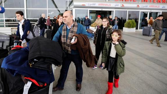 Familia abandona el aeropuerto de Erbil, en Irak, tras quedarse en tierra.